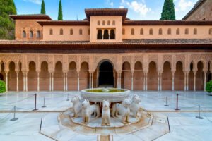 The iconic Lion Fountain at the heart of the Court of the Lions in the Alhambra’s Nasrid Palaces, Granada, Spain.