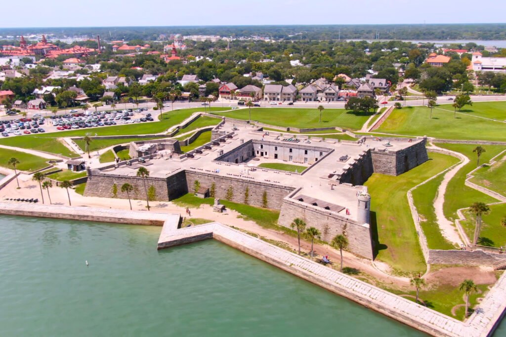 Vista aérea del Castillo de San Marcos en St. Augustine, Florida, mostrando el patio interior del fuerte, los baluartes, el muro costero y las calles cercanas de la ciudad.