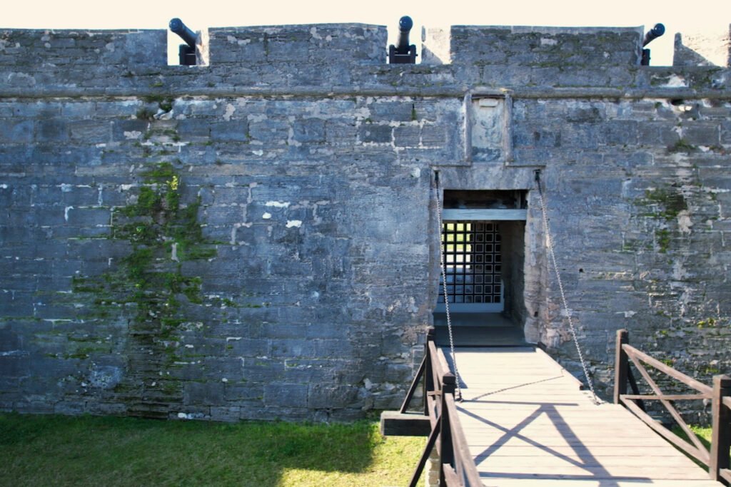 Puente levadizo y puerta de entrada principal del Castillo de San Marcos en St. Augustine, Florida, con muros de coquina desgastados y cañones montados en la parte superior.
