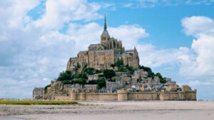 Mont-Saint-Michel rising above the tidal sands in Normandy, France, with dramatic stone walls and abbey.