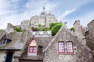 Stone houses with Mont-Saint-Michel abbey above on a sunny day.