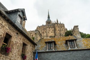 Stone buildings and abbey spire at Mont-Saint-Michel on a cloudy day.