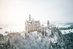 Neuschwanstein Castle covered in snow, surrounded by a winter landscape in the Bavarian Alps.