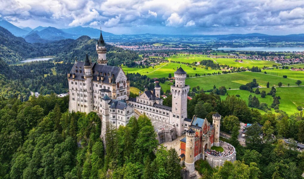 Aerial view of Neuschwanstein Castle surrounded by green valleys and mountains in Bavaria, Germany