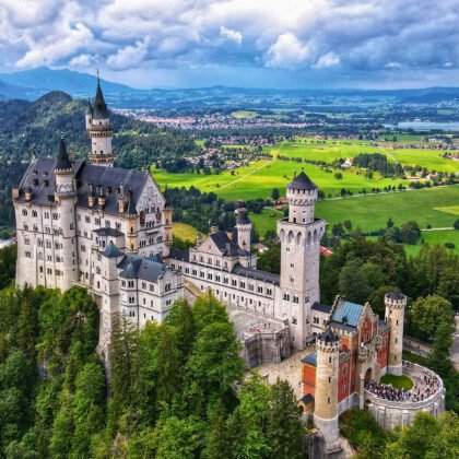 Aerial view of Neuschwanstein Castle surrounded by green valleys and mountains in Bavaria, Germany