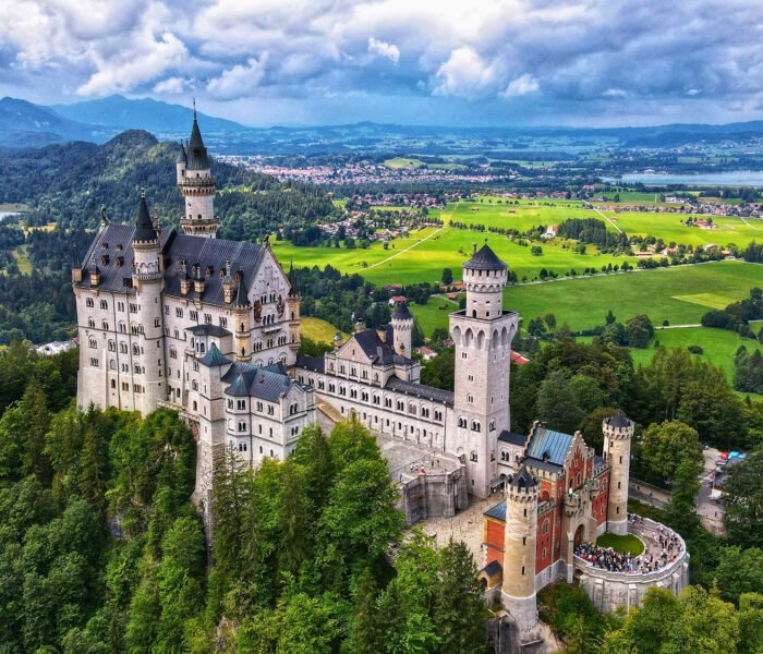 Aerial view of Neuschwanstein Castle surrounded by green valleys and mountains in Bavaria, Germany