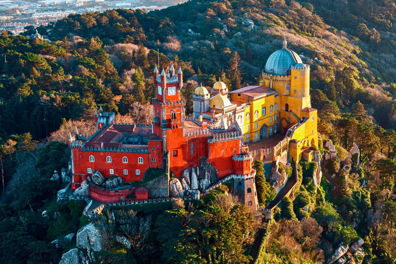 Pena Palace glowing in golden hour light, nestled in the hills above Sintra.