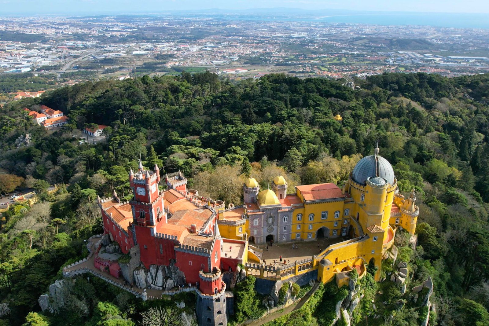 A panoramic aerial look at Pena Palace overlooking Sintra’s woodlands and the Atlantic beyond.