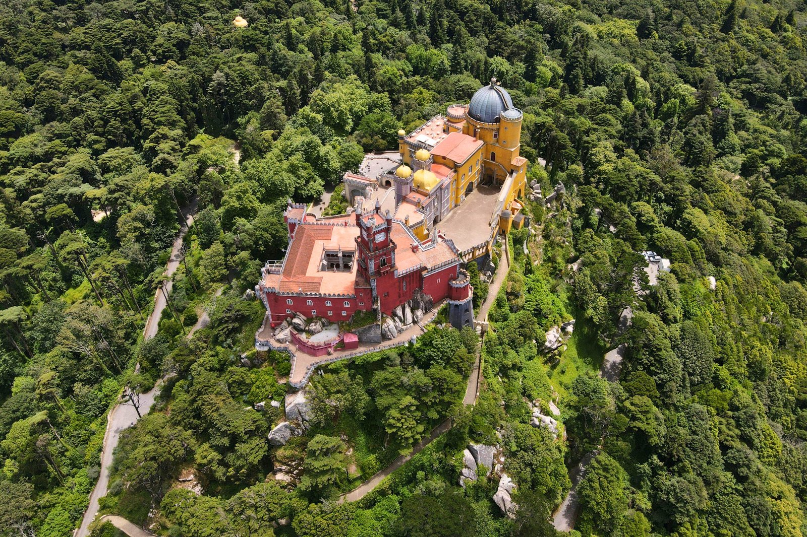 Aerial perspective of Pena Palace surrounded by the dense greenery of the Sintra mountains.