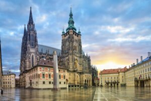 Prague Castle illuminated by sunrise with gothic and baroque architecture in view.
