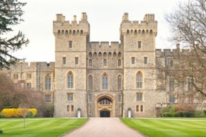 A grand frontal view of Windsor Castle’s imposing entrance, featuring its twin stone towers, arched gateway, and meticulously maintained lawns leading up to the historic royal residence.