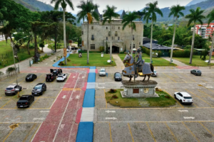 Entrance to Castelo de Itaipava with a medieval knight statue on horseback in the foreground, palm-lined pathways, and parked cars in the visitor lot.