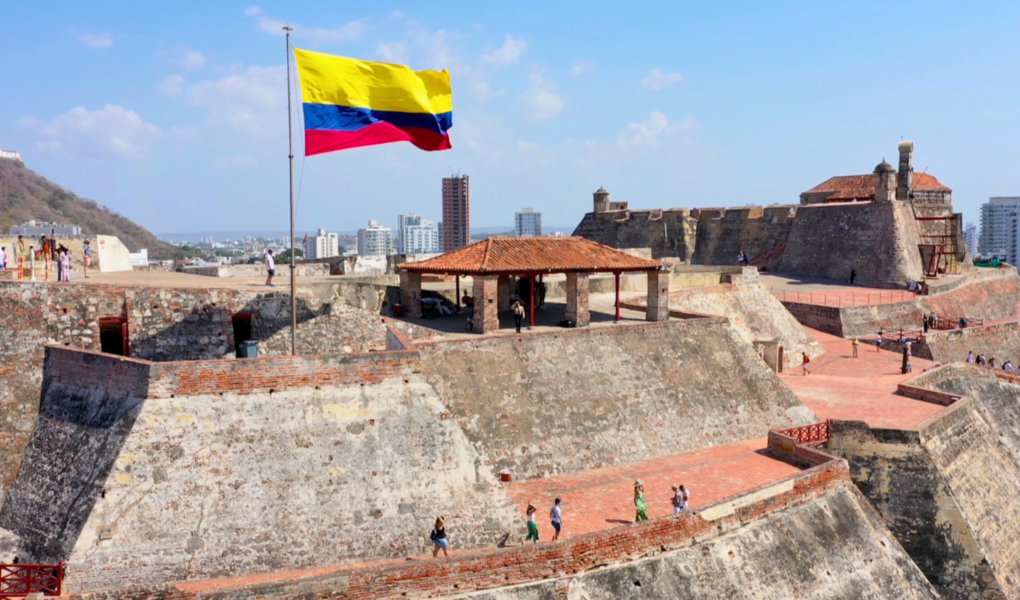 Visitors exploring Castillo San Felipe de Barajas in Cartagena, Colombia, with the Colombian flag waving above the historic stone fortress.