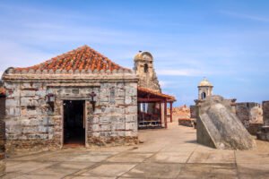 Historic stone buildings and towers at Castillo San Felipe de Barajas under blue sky.