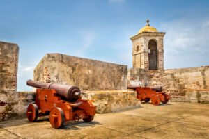 Historic cannons at Castillo San Felipe de Barajas in Cartagena under blue sky.