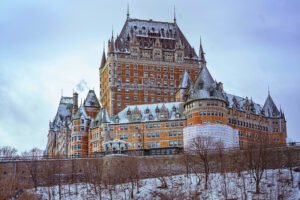 Close-up winter view of Fairmont Le Château Frontenac in Québec City, Canada, with snow-dusted rooftops and a partially wrapped turret under renovation.