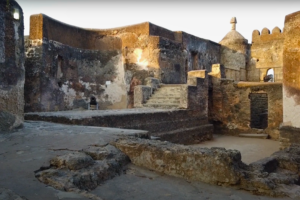 Interior courtyard of Fort Jesus in Mombasa, featuring weathered coral stone walls, historic staircases, and a preserved Portuguese-era cannon.