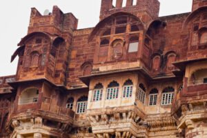 Close-up view of the intricately carved upper balconies and jharokhas of Mehrangarh Fort in Jodhpur, showcasing Rajput architectural details in red sandstone.