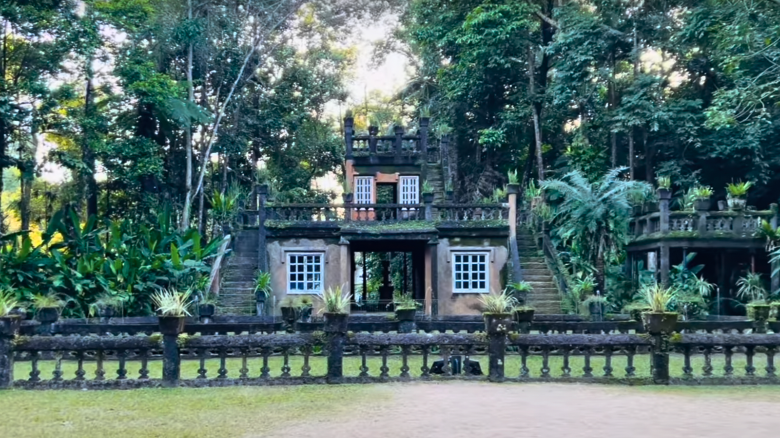 Front view of Paronella Park Castle surrounded by lush rainforest greenery.