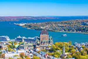Aerial view of Fairmont Le Château Frontenac and Old Quebec City with the St. Lawrence River and cruise ships in the background on a bright autumn day.