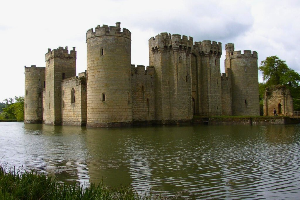 Bodiam Castle in England, a 14th-century Gothic-style fortress with round towers and a wide moat reflecting late medieval architectural elegance.