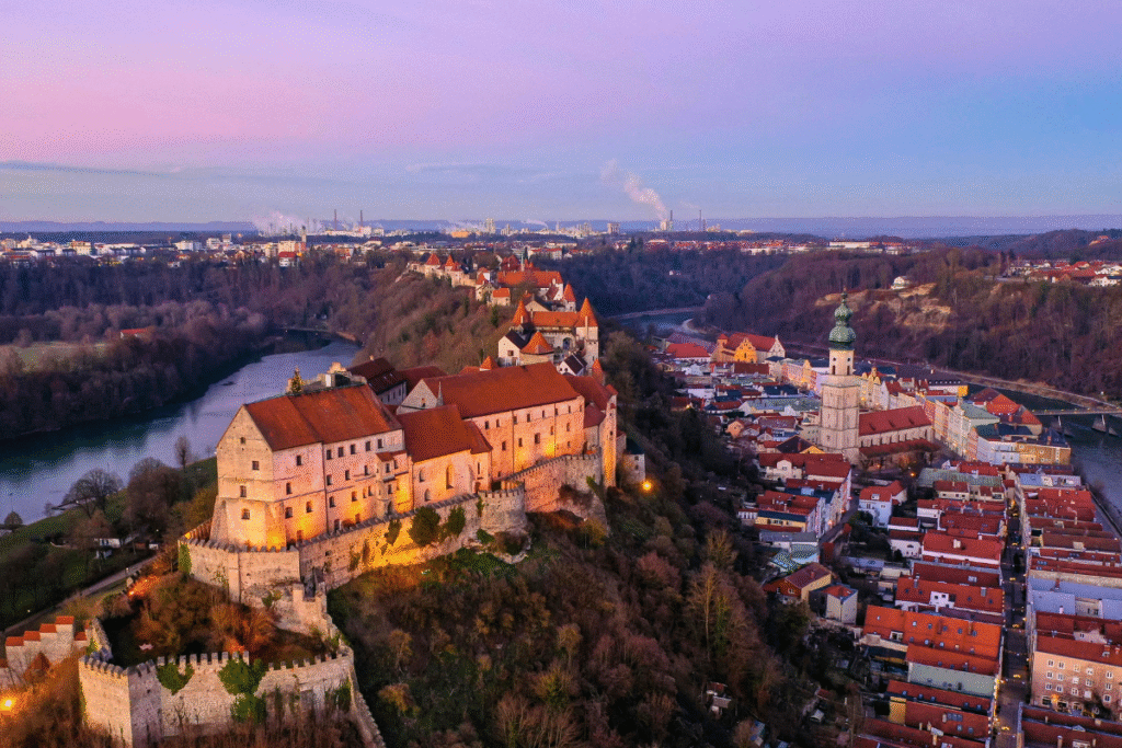 Aerial view of Burghausen Castle at twilight, stretching above the old town and the Salzach River in Bavaria, Germany.
