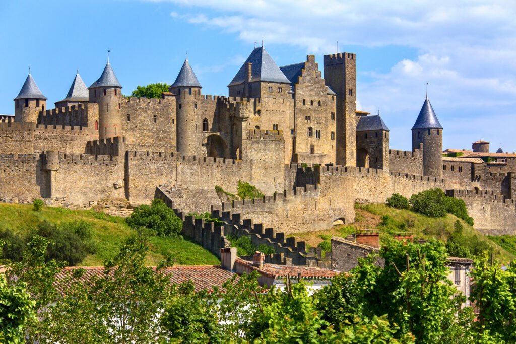 Medieval stone fortress of Carcassonne in France, featuring double curtain walls, towers, and battlements under a blue sky.
