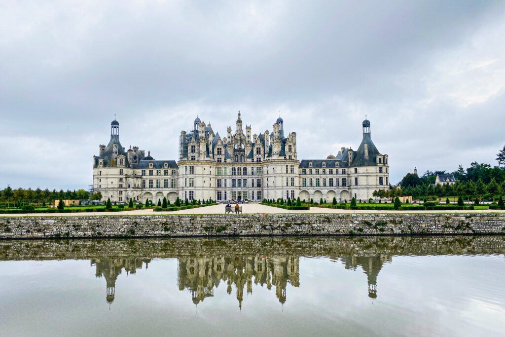 Front view of Château de Chambord with its reflection in the moat on a cloudy day