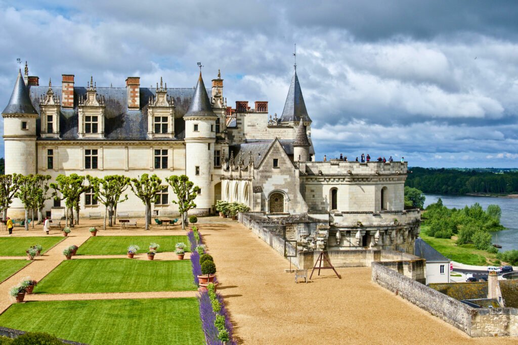 Château d’Amboise with manicured gardens, trimmed trees, and visitors standing on the panoramic terrace overlooking the Loire River