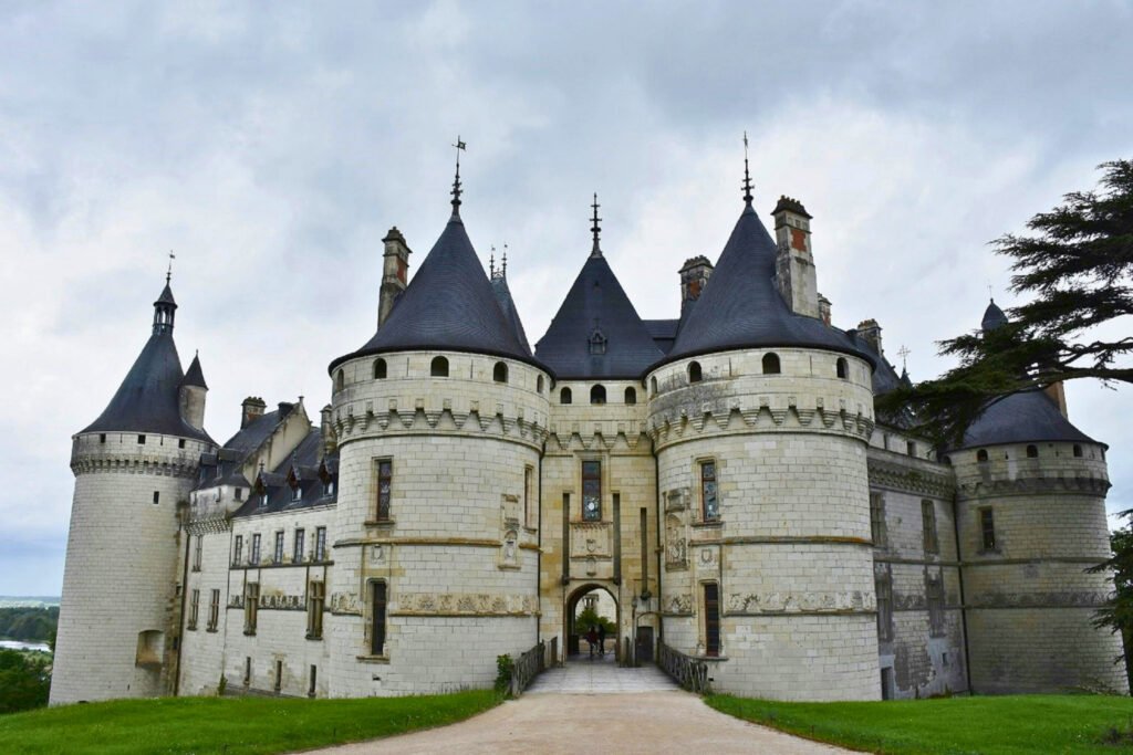 Front view of Château de Chaumont-sur-Loire with round towers, conical roofs, and a central arched entrance on a cloudy day