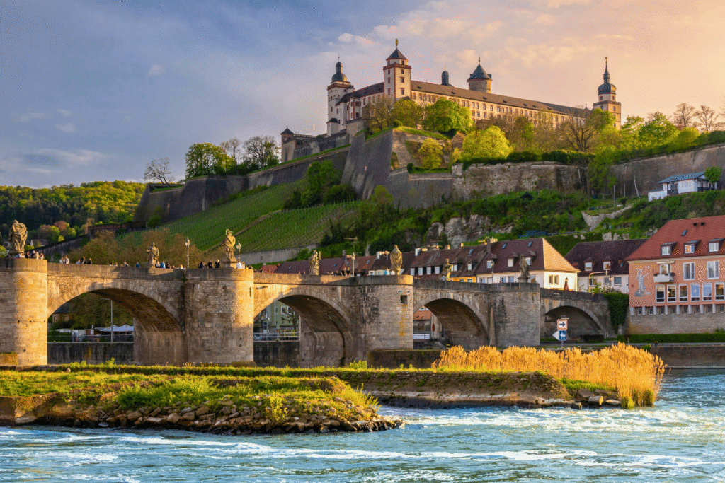 View of Fortress Marienberg above the Alte Mainbrücke bridge at sunset in Würzburg, Germany.