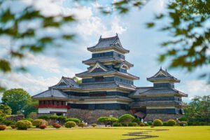 Matsumoto Castle in Japan with landscaped gardens under blue sky.