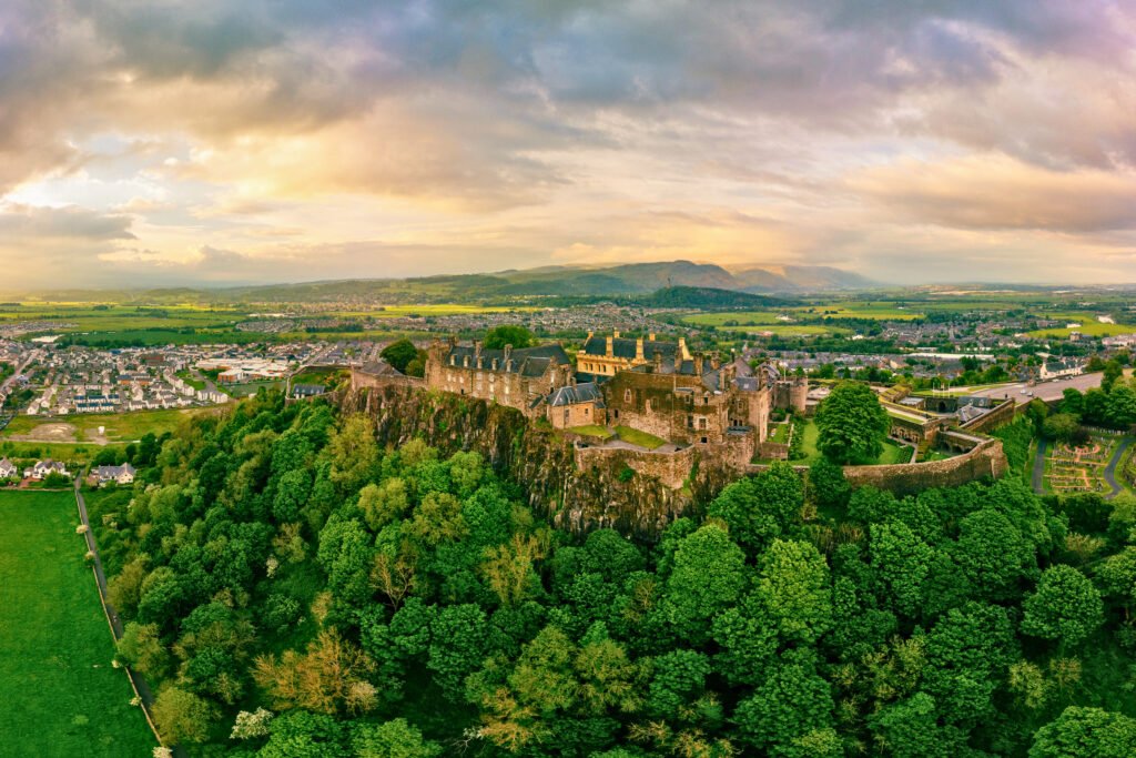 Dramatic aerial view of Stirling Castle perched on a rocky hilltop surrounded by green fields and the Scottish countryside