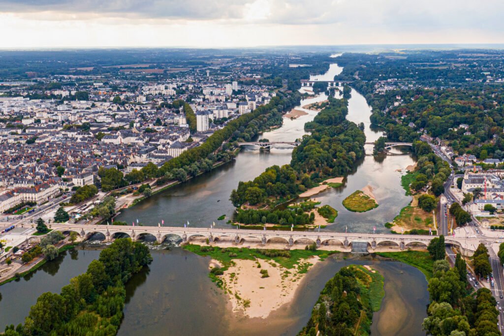 Aerial view of Tours, France with the Napoleon Bridge crossing the Loire River and islands dotting the water beneath a cloudy sky