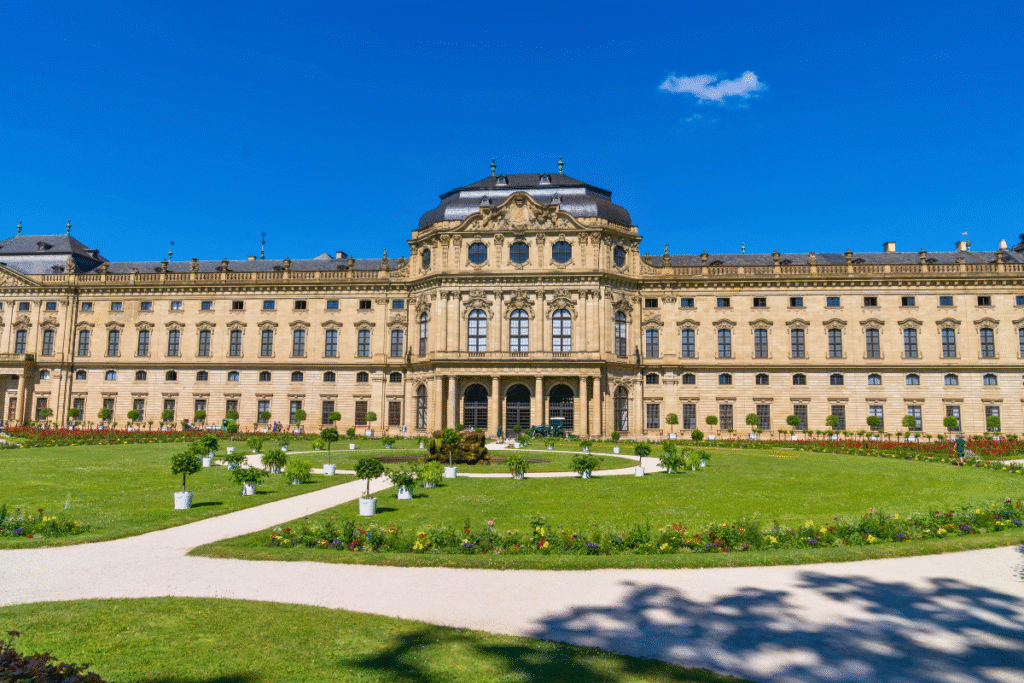 Würzburg Residence seen from the Court Garden, with Baroque architecture and manicured lawns under a bright blue sky.
