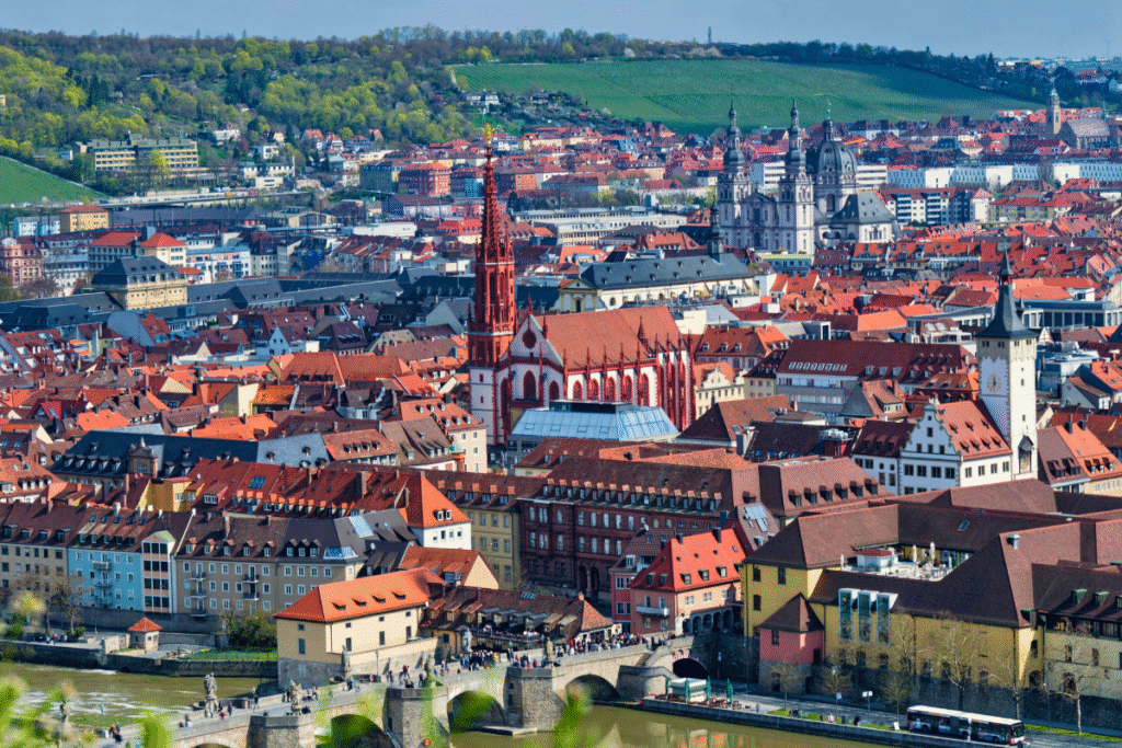 Aerial view of Würzburg’s Old Town featuring the red spire of Marienkapelle and the Alte Mainbrücke over the Main River.