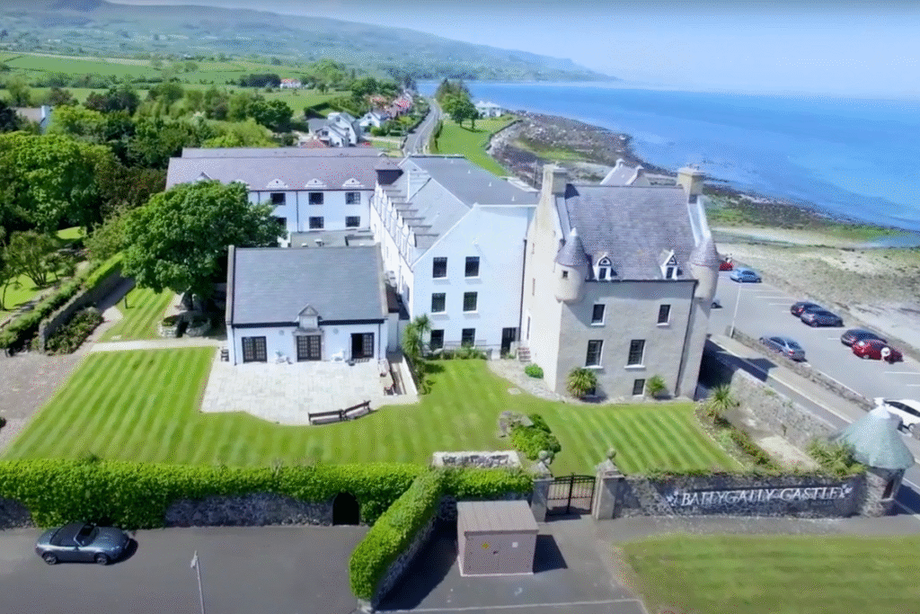 Aerial view of Ballygally Castle in Northern Ireland, with its manicured gardens and coastal location overlooking the sea.