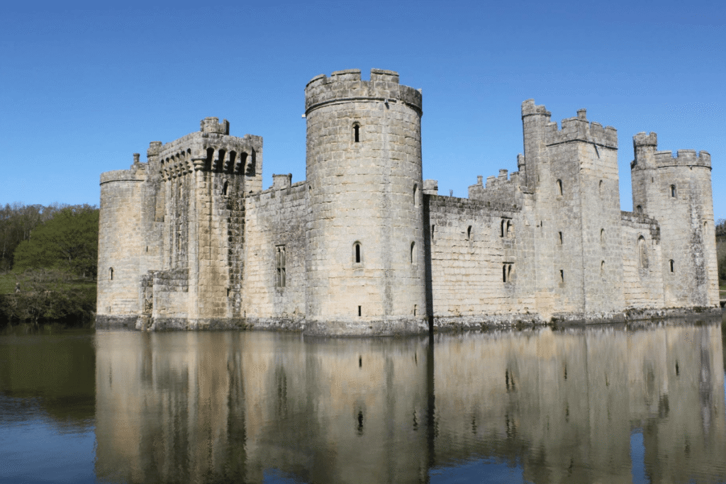 Bodiam Castle’s stone towers and walls reflected perfectly in the still water of its surrounding moat on a sunny day.