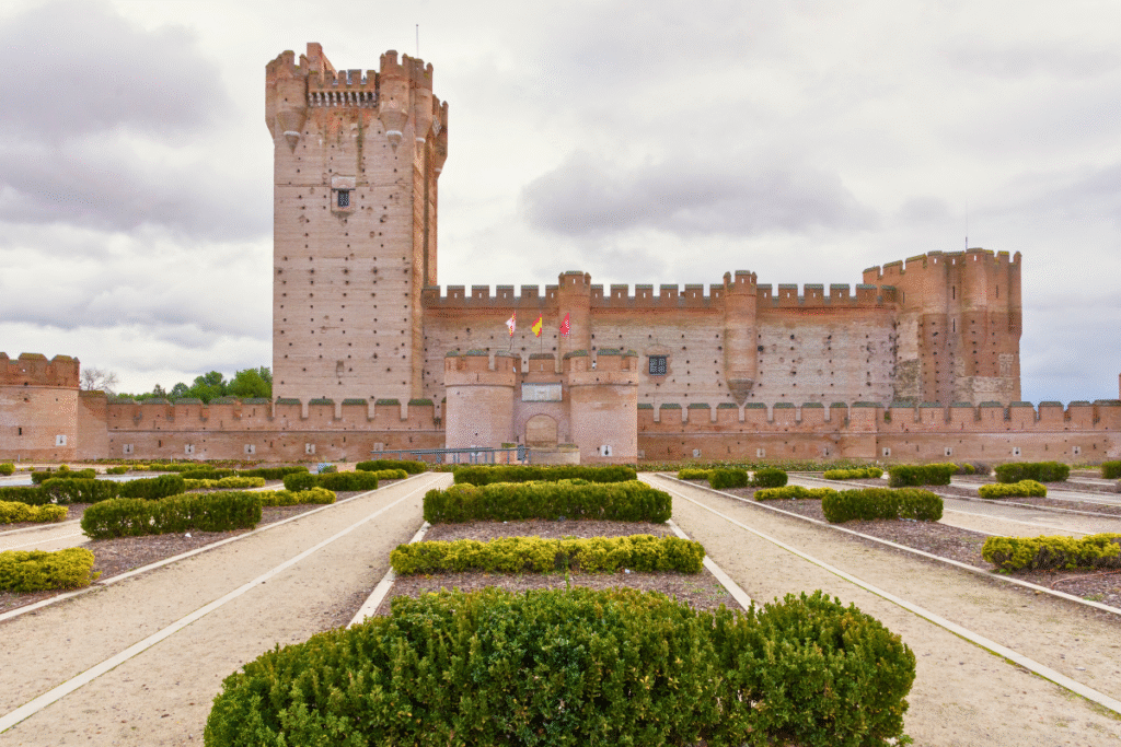 Castillo de la Mota’s massive red-brick walls and towering keep with garden paths in Medina del Campo, Spain