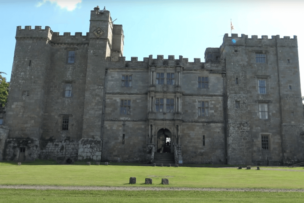Front view of Chillingham Castle, England, showing its imposing stone facade and battlements under a clear blue sky.