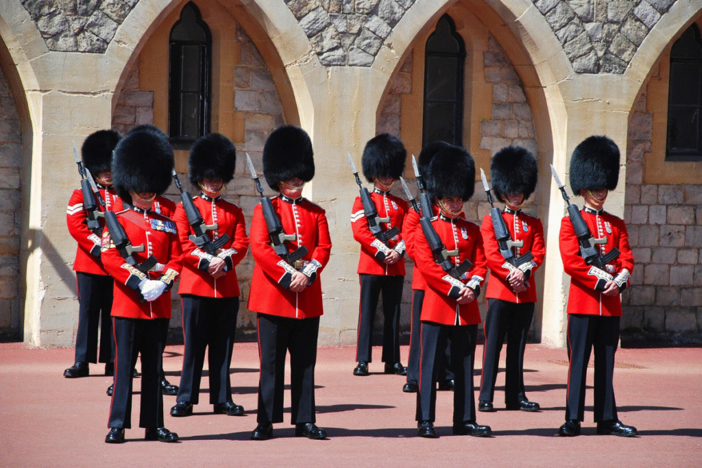 Guards in red uniforms and bearskin hats standing at attention during the Changing of the Guard ceremony at Windsor Castle.