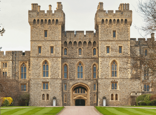 Front view of Windsor Castle’s main entrance, with symmetrical towers, stone walls, and manicured lawns.