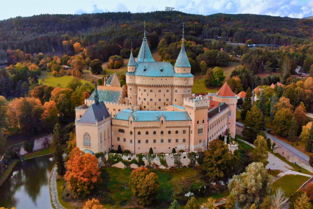 Aerial view of Bojnice Castle surrounded by vibrant autumn trees and lush greenery.