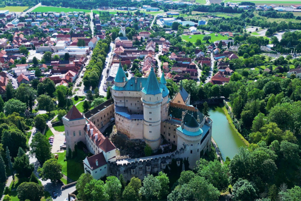 Aerial view of Bojnice Castle surrounded by lush greenery and picturesque town.