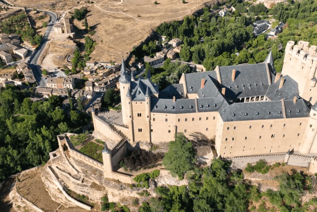 Aerial view of Alcázar of Segovia, a historic Spanish castle with towers and gardens.