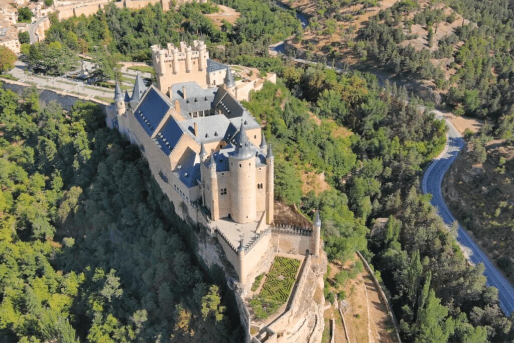 Aerial view of Segovia Castle surrounded by lush forest in Spain.