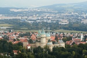 Bojnice Castle Slovakia surrounded by trees and town rooftops with city in background