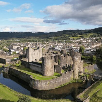 Caerphilly Castle surrounded by moat and Welsh hills, showcasing medieval architecture.