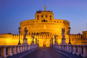 Castel Sant'Angelo glowing at dusk with angel statues on the bridge.