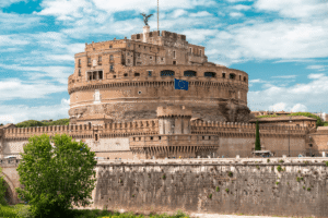 Ancient Castel Sant'Angelo fortress in Rome with a European Union flag and blue sky above.